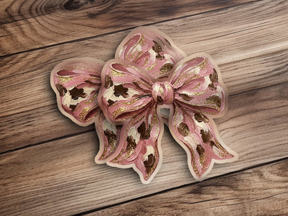 Pink bow with gold glitter accents on a wooden background.