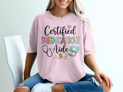 Pink t-shirt with "Certified Medication Aide" text and medical illustrations.