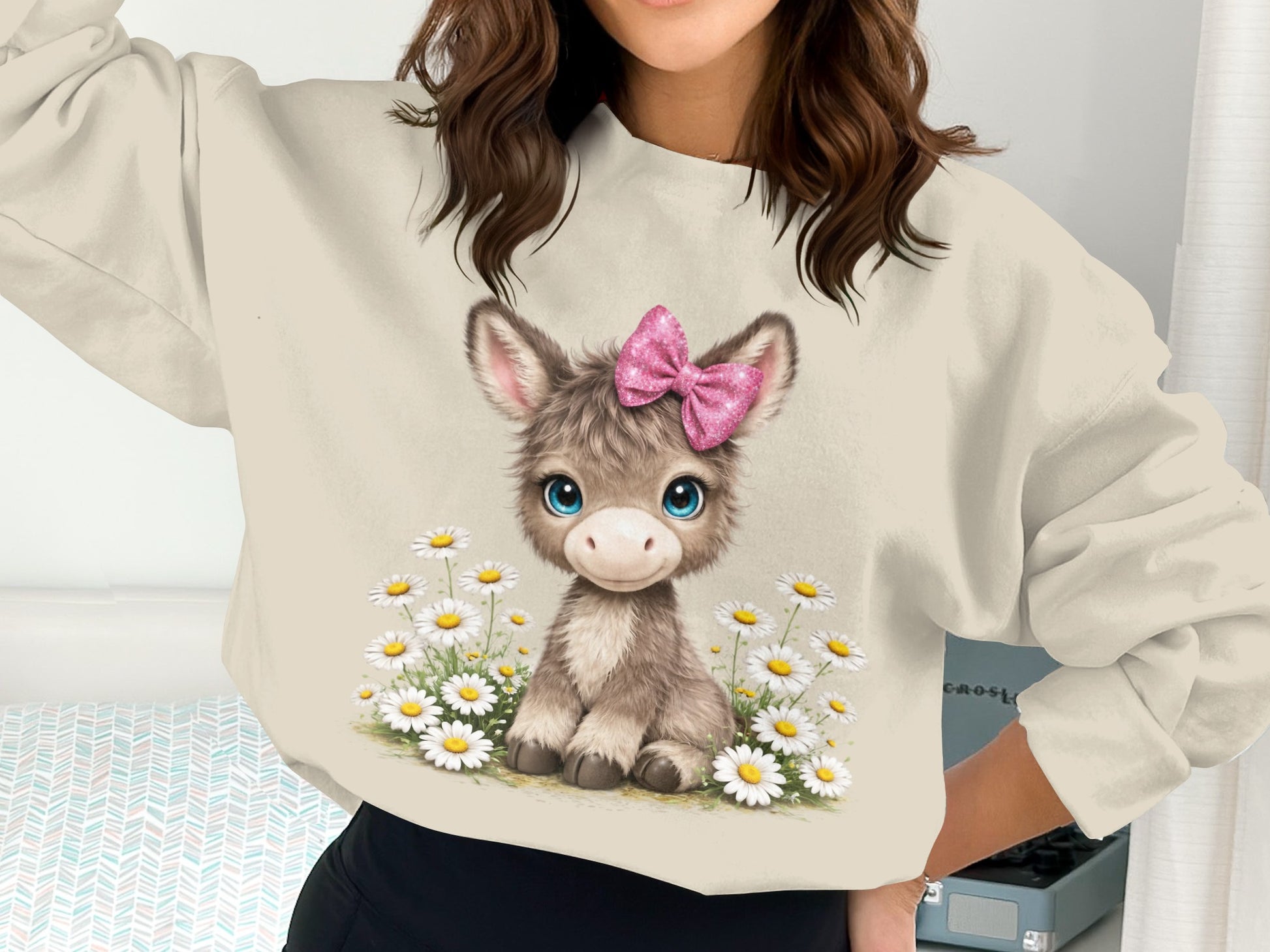 Cute donkey with pink bow sitting among daisies on a light sweatshirt.