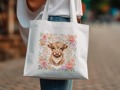 White tote bag featuring a Highland cow illustration with floral accents.