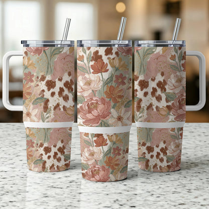 Floral cow print tumbler with straw and handle.