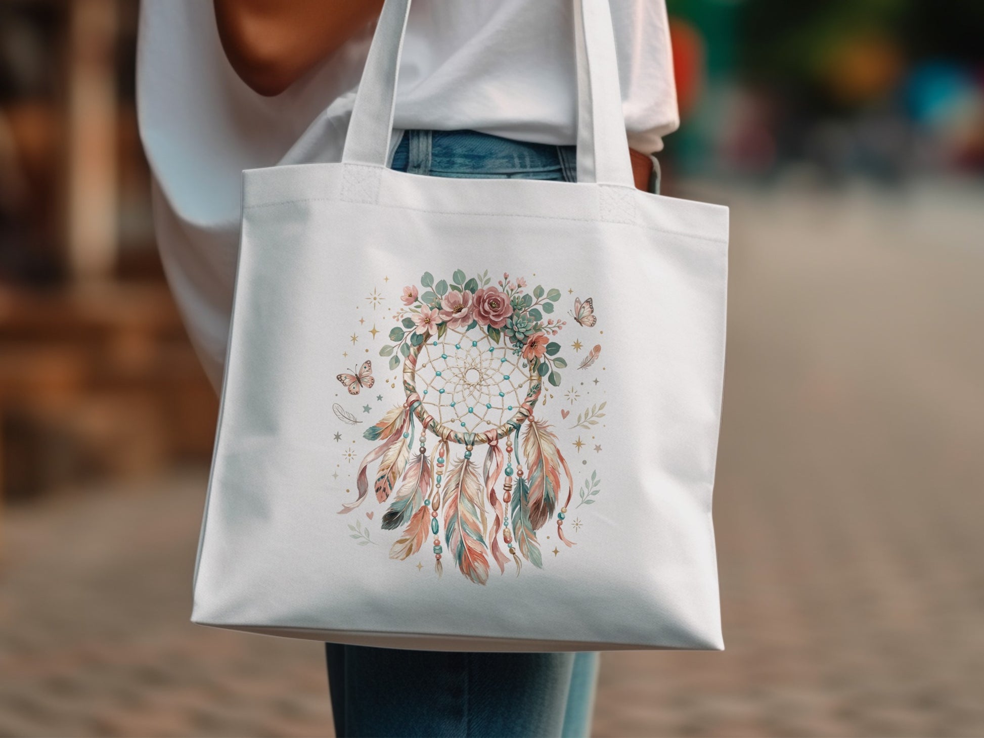 White tote bag with a dreamcatcher design featuring flowers, feathers, and butterflies.