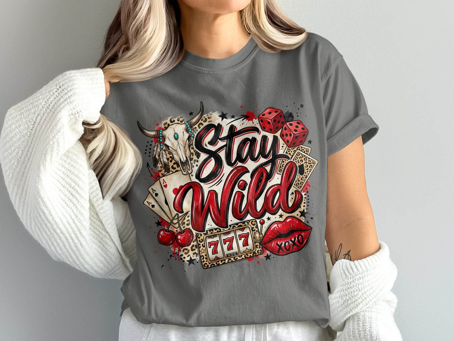 Skull, dice, cards, cherries, lips, and "Stay Wild" text on a gray t-shirt.