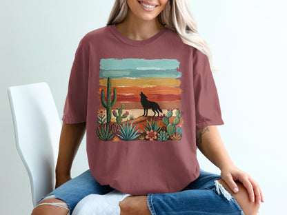 Woman wearing maroon t-shirt with desert sunset and wolf graphic.