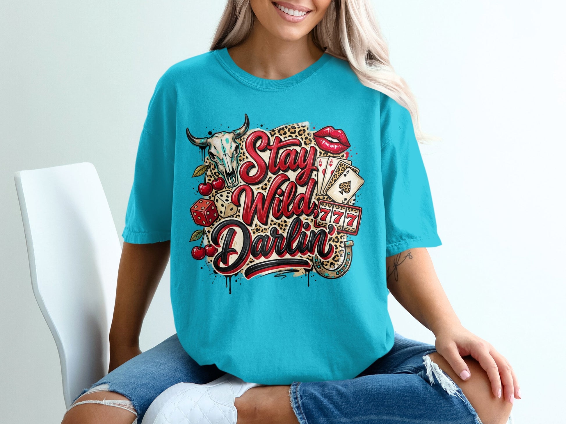 Teal t-shirt with "Stay Wild Darlin'" text and graphic of a bull skull, lips, and playing cards.