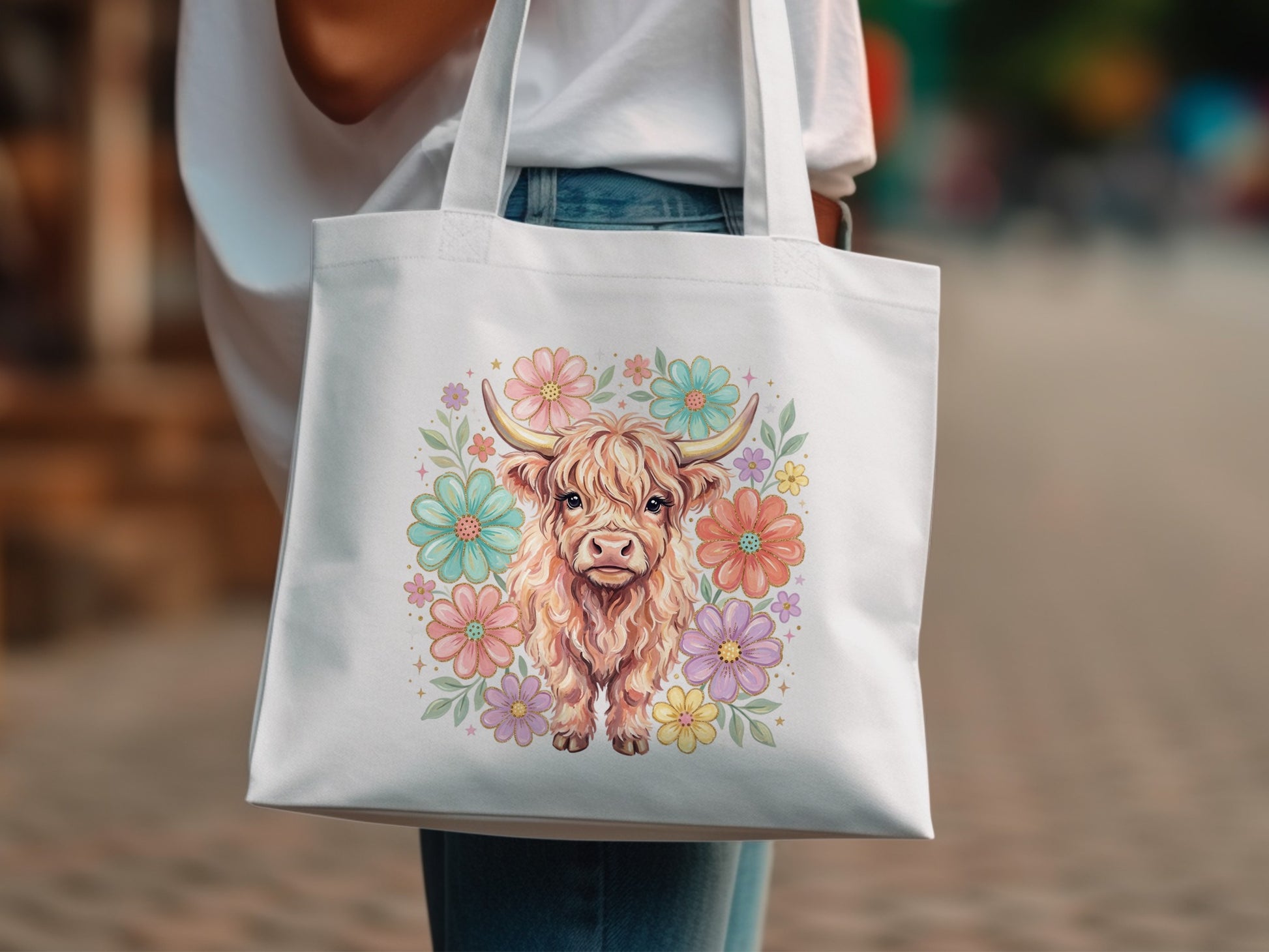 Tote bag with a watercolor painting of a fluffy Highland cow surrounded by flowers.