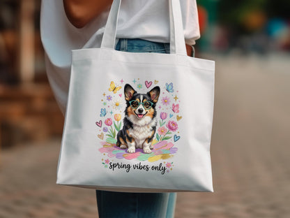 Corgi dog with glasses surrounded by flowers and butterflies on a tote bag.