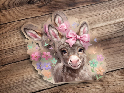 Donkey sticker with pink bow and colorful flowers on wood background.