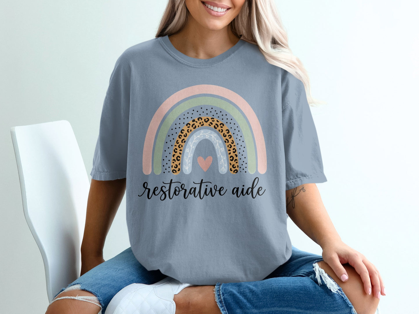 Gray t-shirt with a pastel rainbow and "Restorative aide" text.