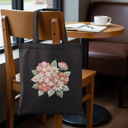 Black tote bag with a floral design featuring pastel checkered and patterned flowers.