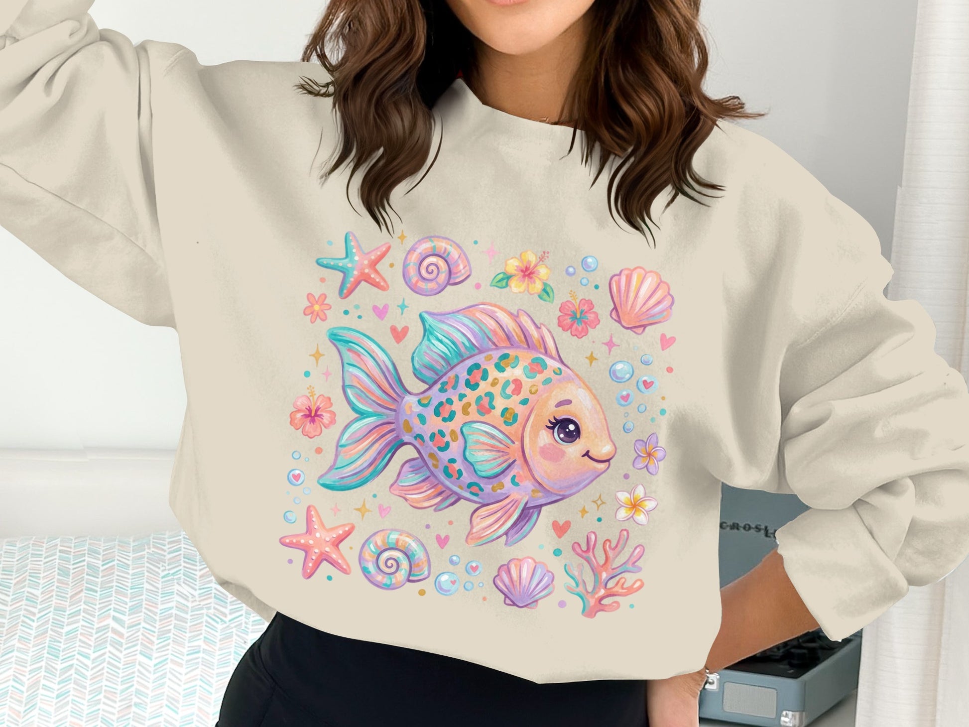 Cream sweatshirt with a colorful cartoon goldfish surrounded by shells and flowers.