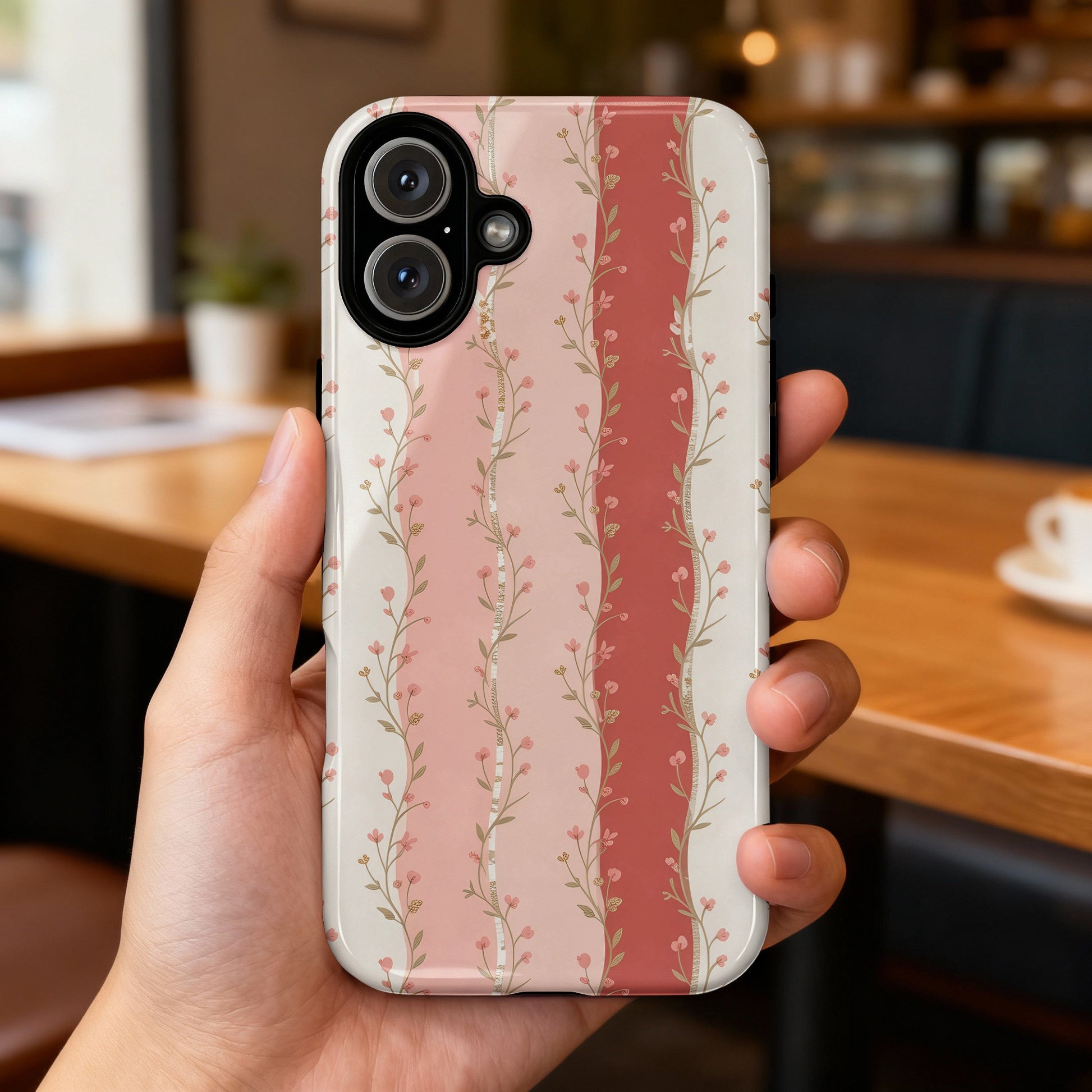 Smartphone case with pink floral stripes on a blurred background.