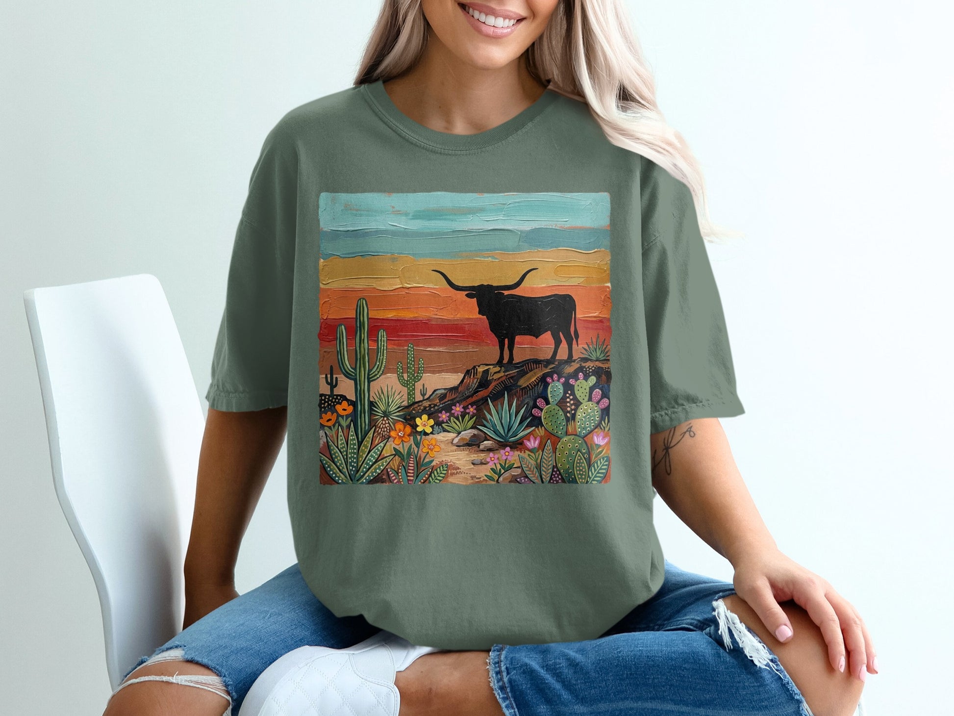 Green t-shirt featuring a desert landscape with a longhorn and colorful painted background.