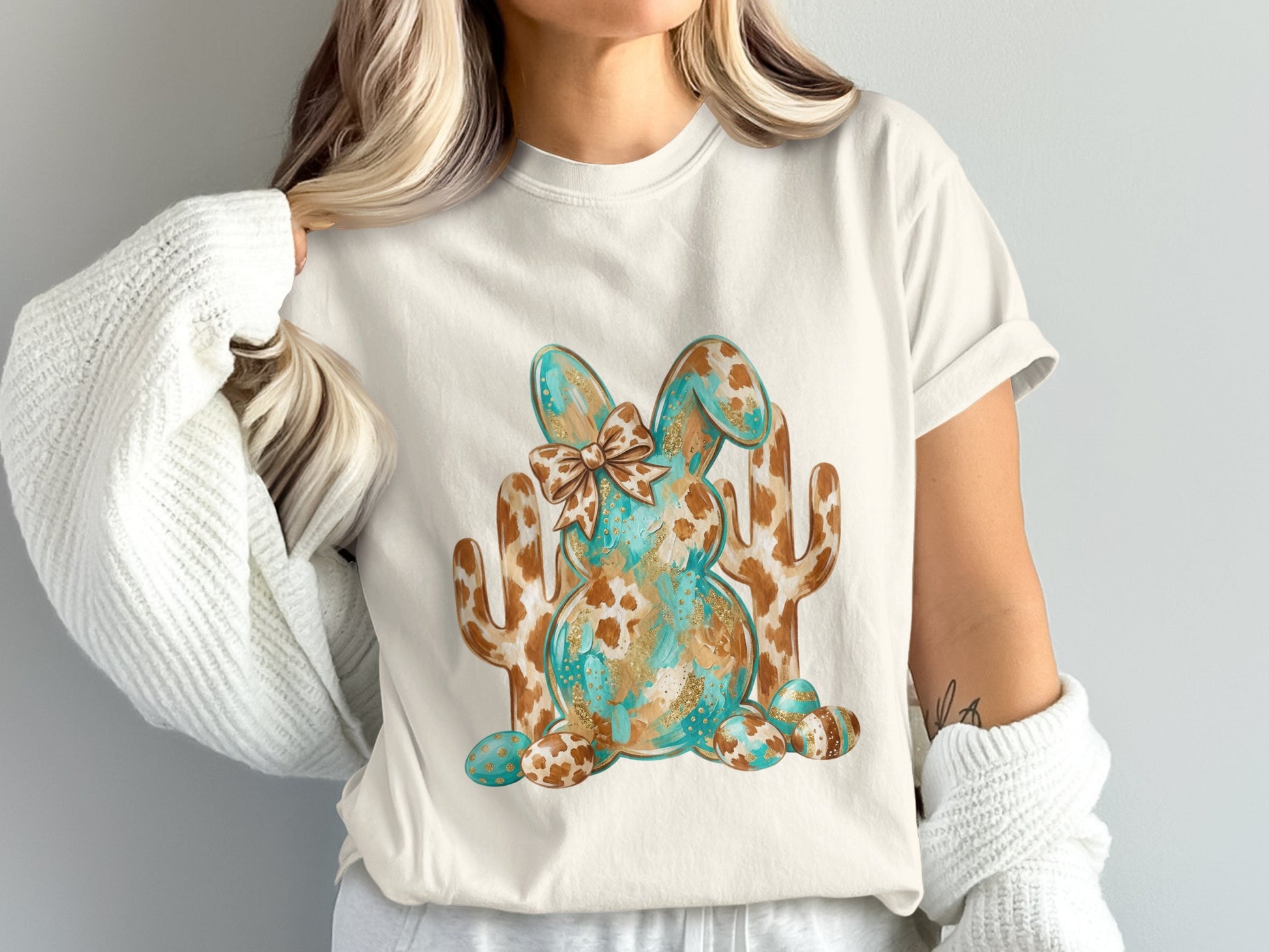 White t-shirt with brown and teal abstract bunny graphic and cacti.