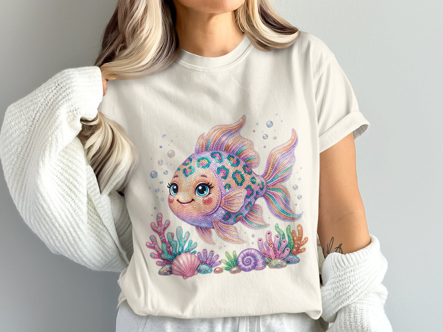 Cream t-shirt with a colorful, cartoon goldfish, seashells, and coral.