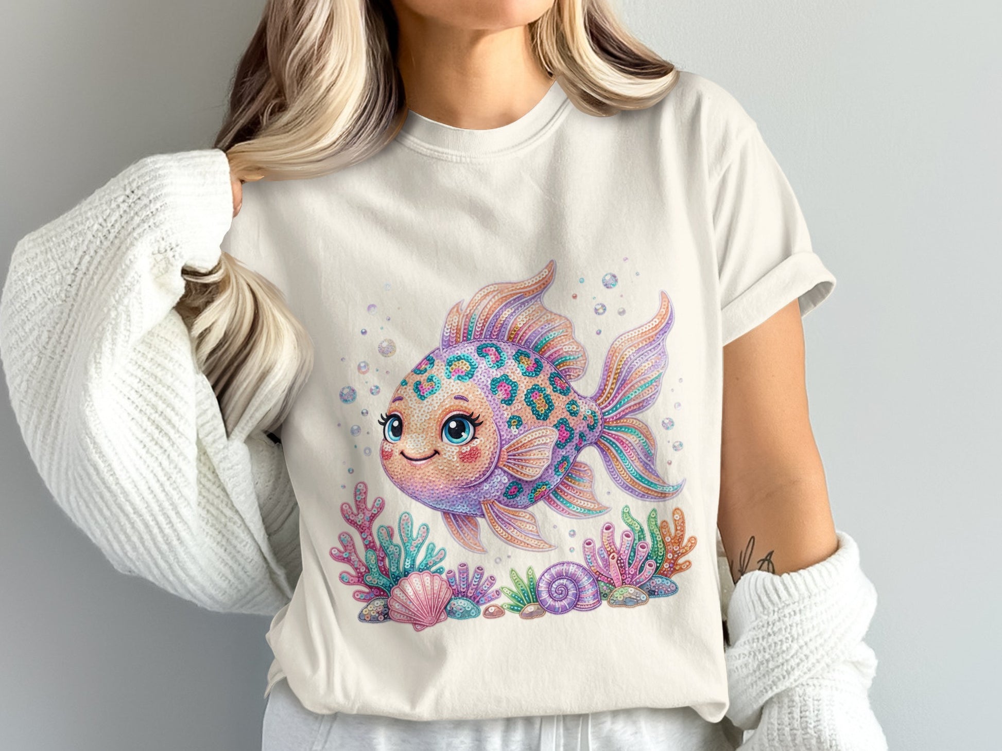 Cream t-shirt with a colorful, cartoon goldfish, seashells, and coral.