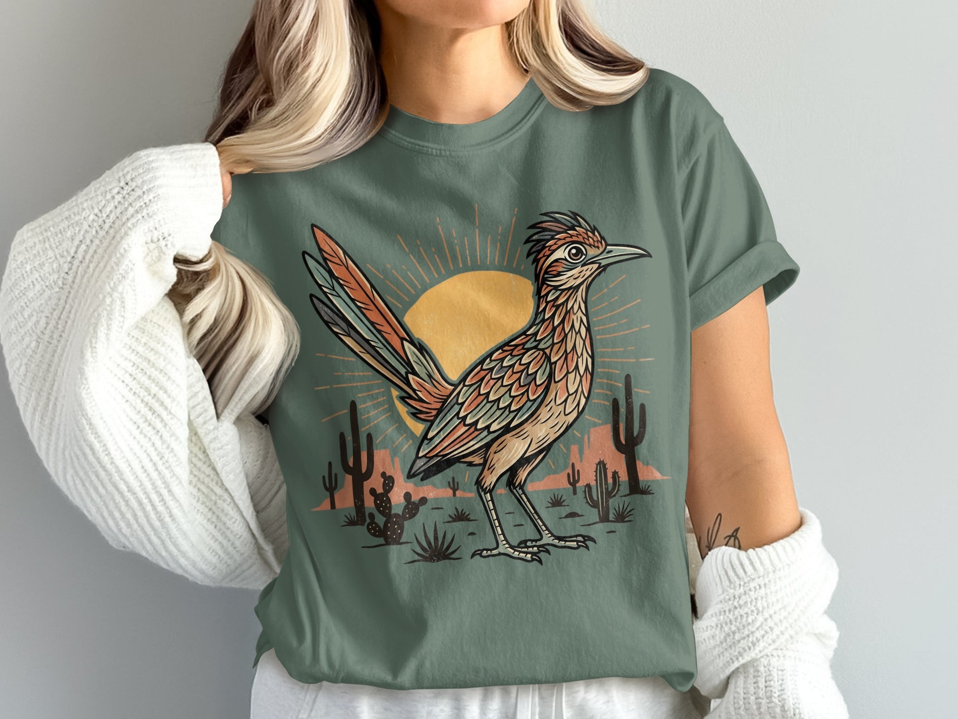 Roadrunner graphic on a dusty green t-shirt with desert sunset and cactus.