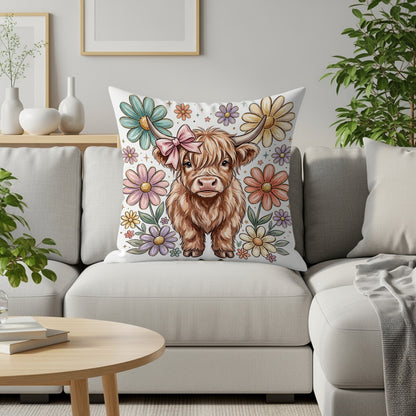Fluffy Highland cow with pink bow on pillow surrounded by colorful flowers.