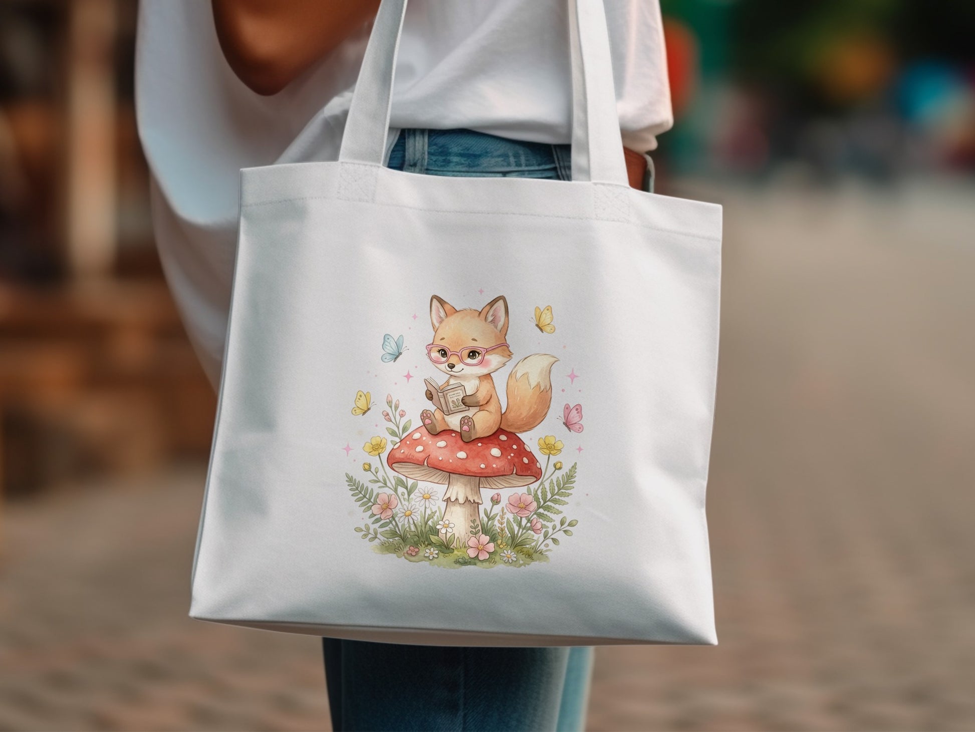 White tote bag with watercolor illustration of a fox reading on a mushroom.