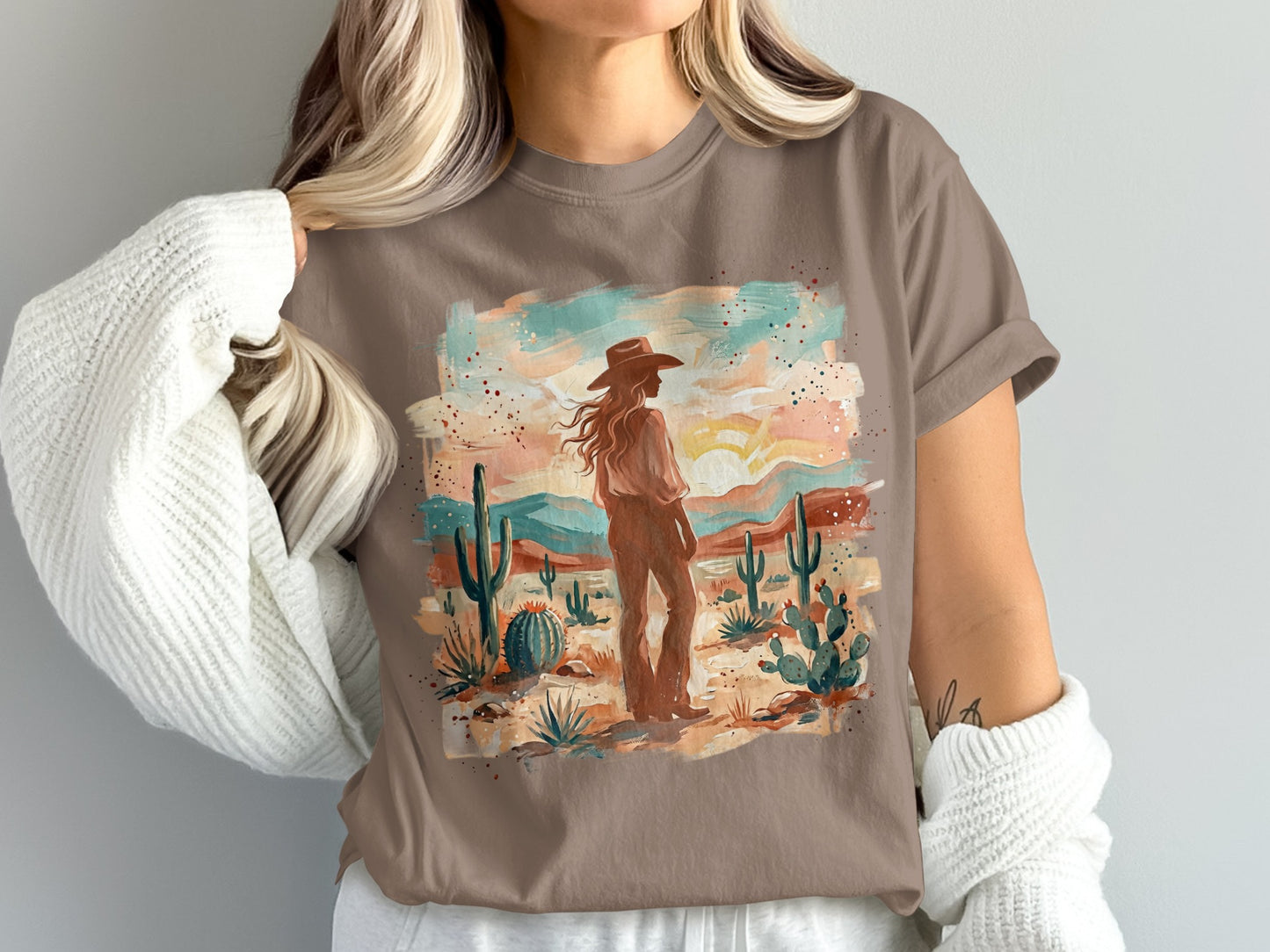 Woman in cowboy hat and western graphic t-shirt in desert landscape.