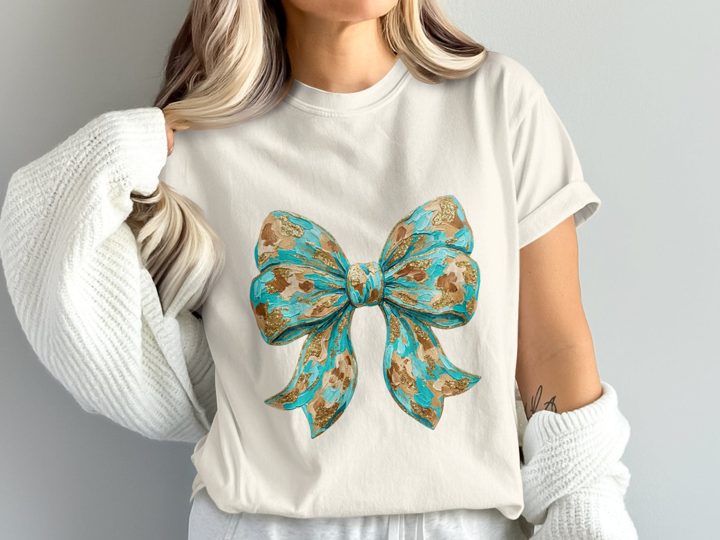 White t-shirt with a large, textured blue and gold bow graphic.