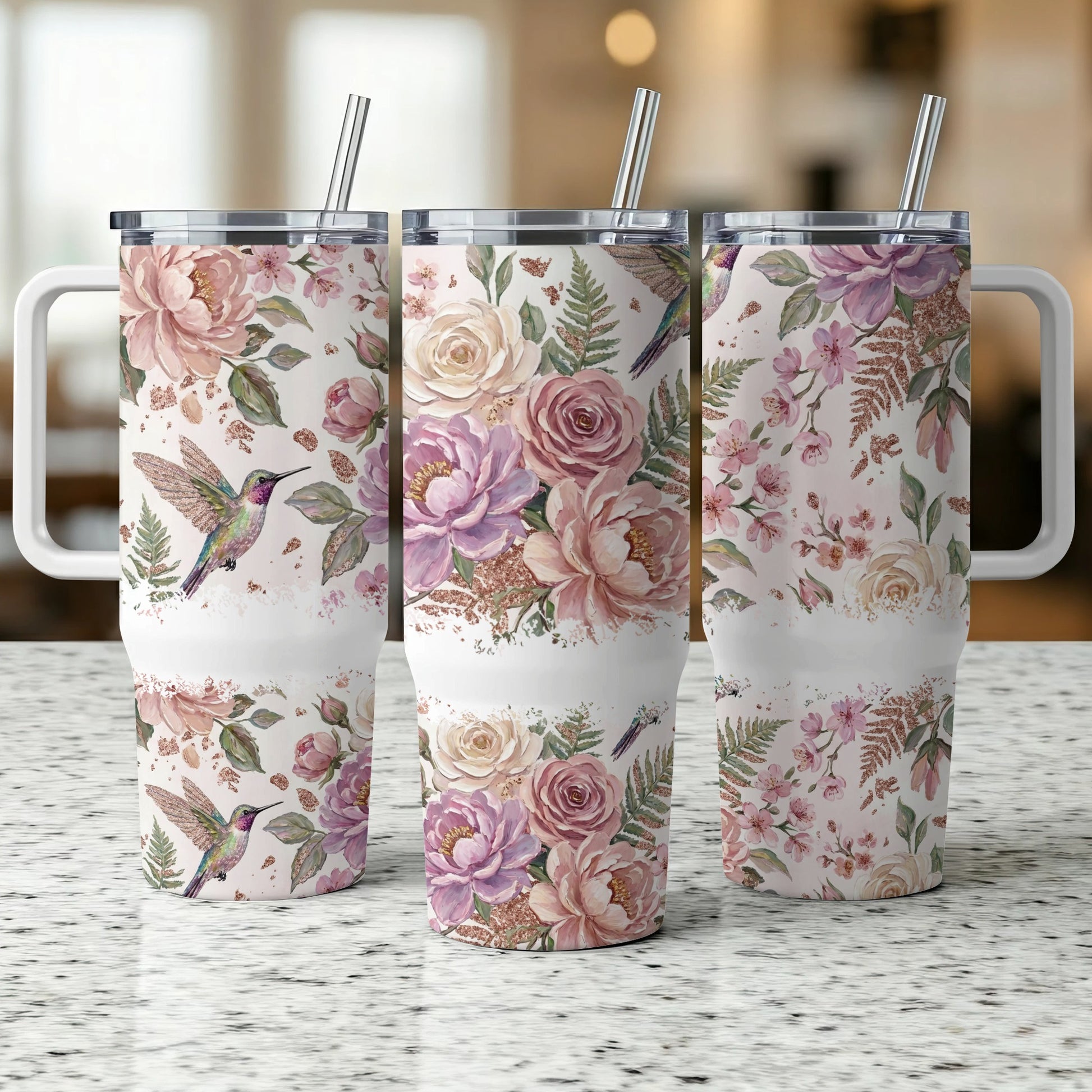Three tumblers with floral and hummingbird pattern, one in focus.