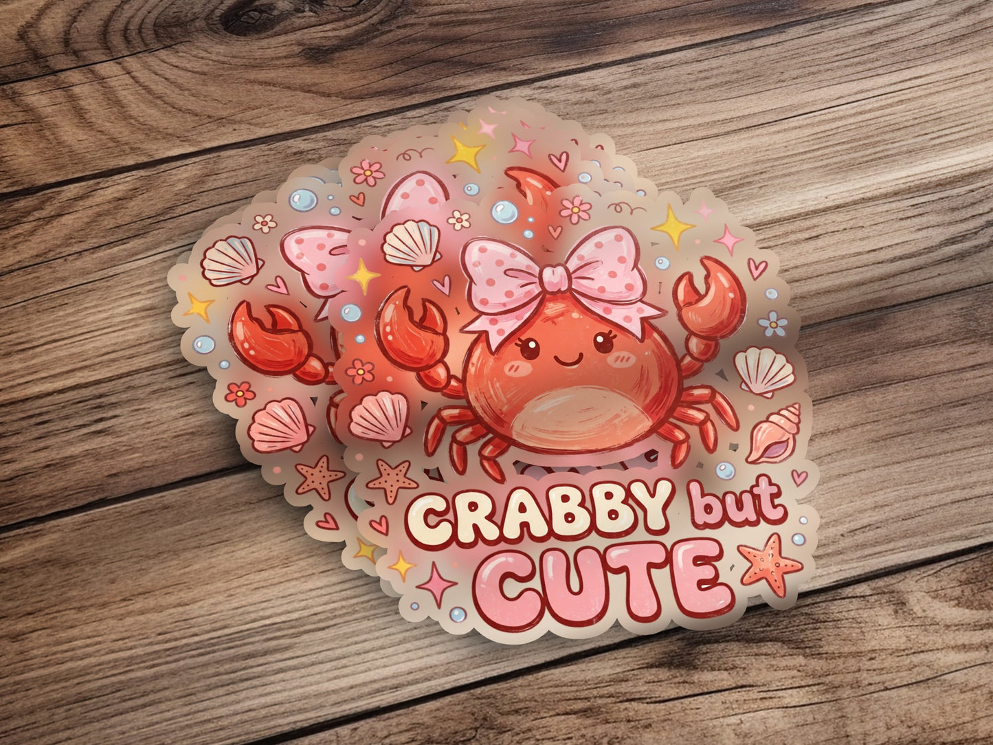 Crab sticker with "Crabby but CUTE" text on wooden background.