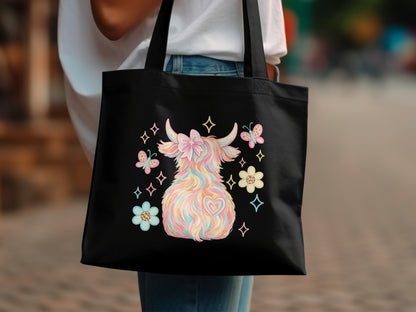 Black tote bag with pastel Highland cow, flowers, and heart design.