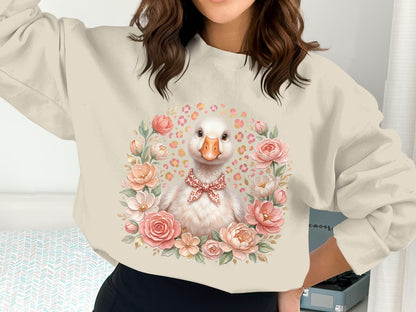 Cream sweatshirt with a duck illustration surrounded by flowers and a red bow tie.